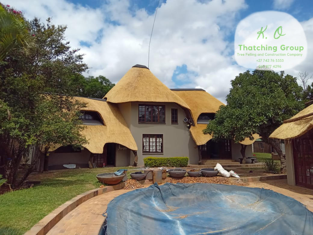 Large thatched house with a pool courtyard surrounded by mature trees